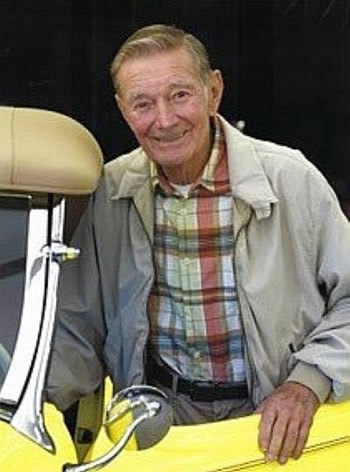 Founder Richard 'Dick' Bertolucci smiling beside his yellow 1930 Chevrolet Sport Roadster