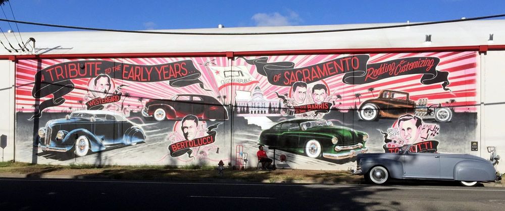 Mural titled A Tribute to the Early Years of Sacramento Rodding and Customizing, with portraits of local hot rod and custom car pioneers including Bertolucci, painted above classic custom cars