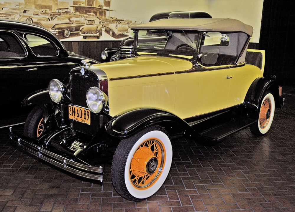 1930 Chevrolet Sport Roadster in yellow with black fenders, orange wire wheels, whitewall tires and a tan top