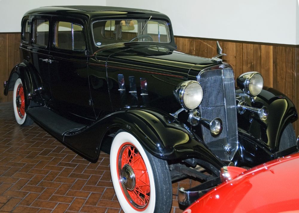 Black 1933 Chevrolet Master 4-door sedan with red wire wheels, whitewall tires and chrome horns