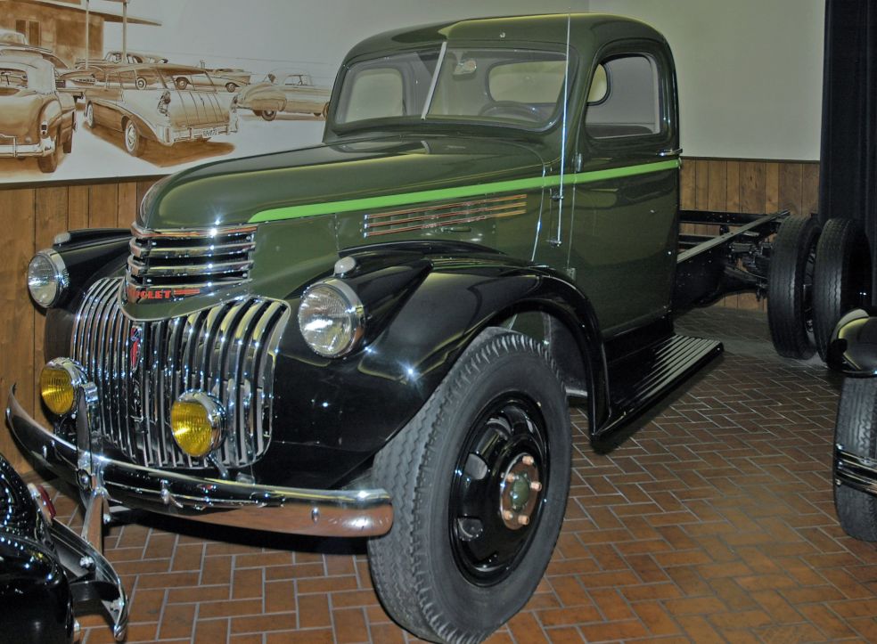 Dark green 1942 Chevrolet 1.5-ton truck with black fenders, a lime green stripe, chrome grille and yellow fog lights