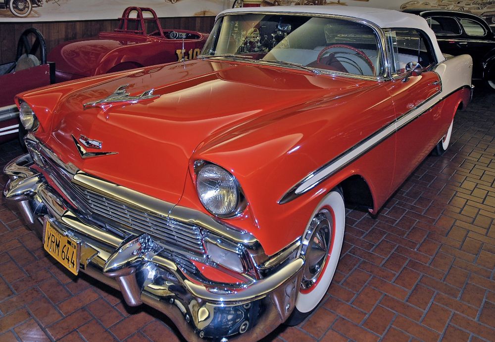 Red and white 1956 Chevrolet Bel Air convertible with a white top, chrome bumpers and whitewall tires
