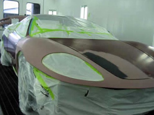 Step 9: Ferrari masked in plastic and green tape inside the paint booth, front panels in sealer