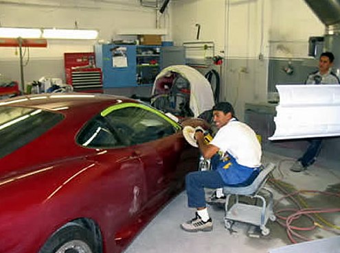 Step 11: Bertolucci's technician polishing the side of the red Ferrari in the shop