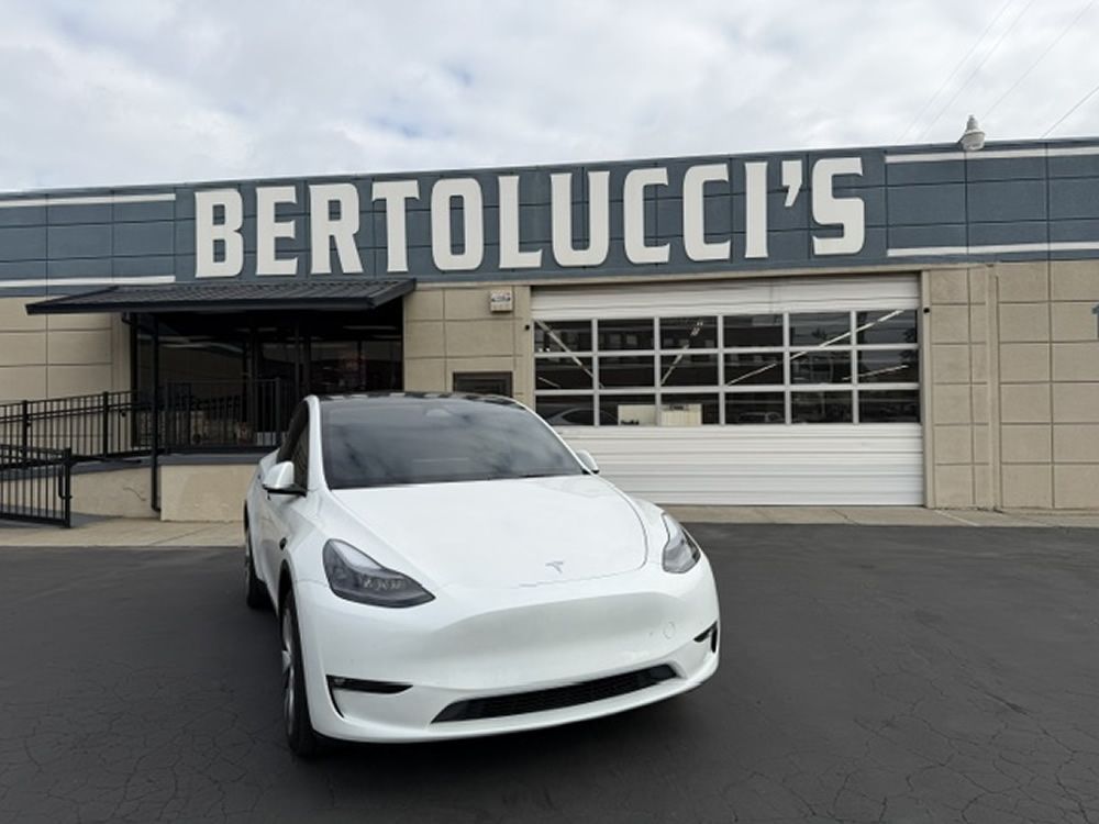 White Tesla Model Y parked in front of Bertolucci's Body & Fender Shop in Sacramento